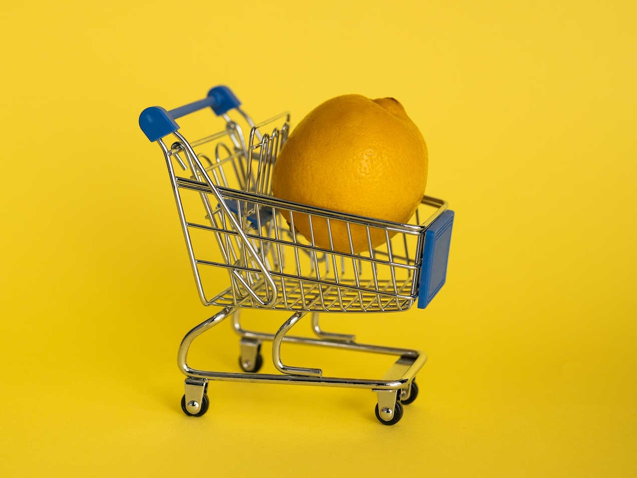 A lemon in a miniature shopping cart